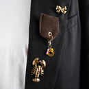 31000 brown ribbon with gold pin with charms on blazer
