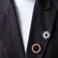 Zwarte blazer met zilveren broche zonnestralen en ronde open roze steentjes broche 