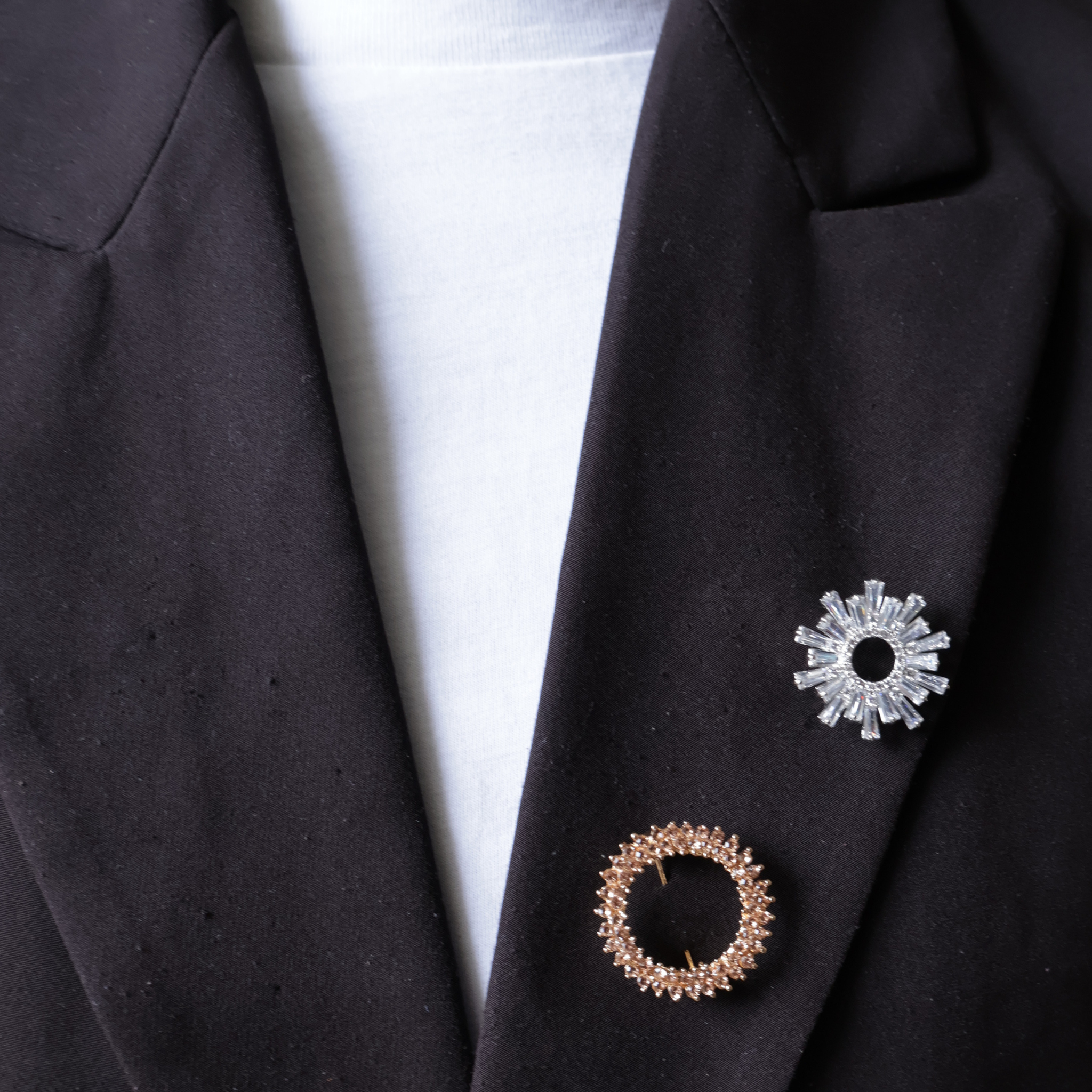 Zwarte blazer met zilveren broche zonnestralen en ronde open roze steentjes broche 