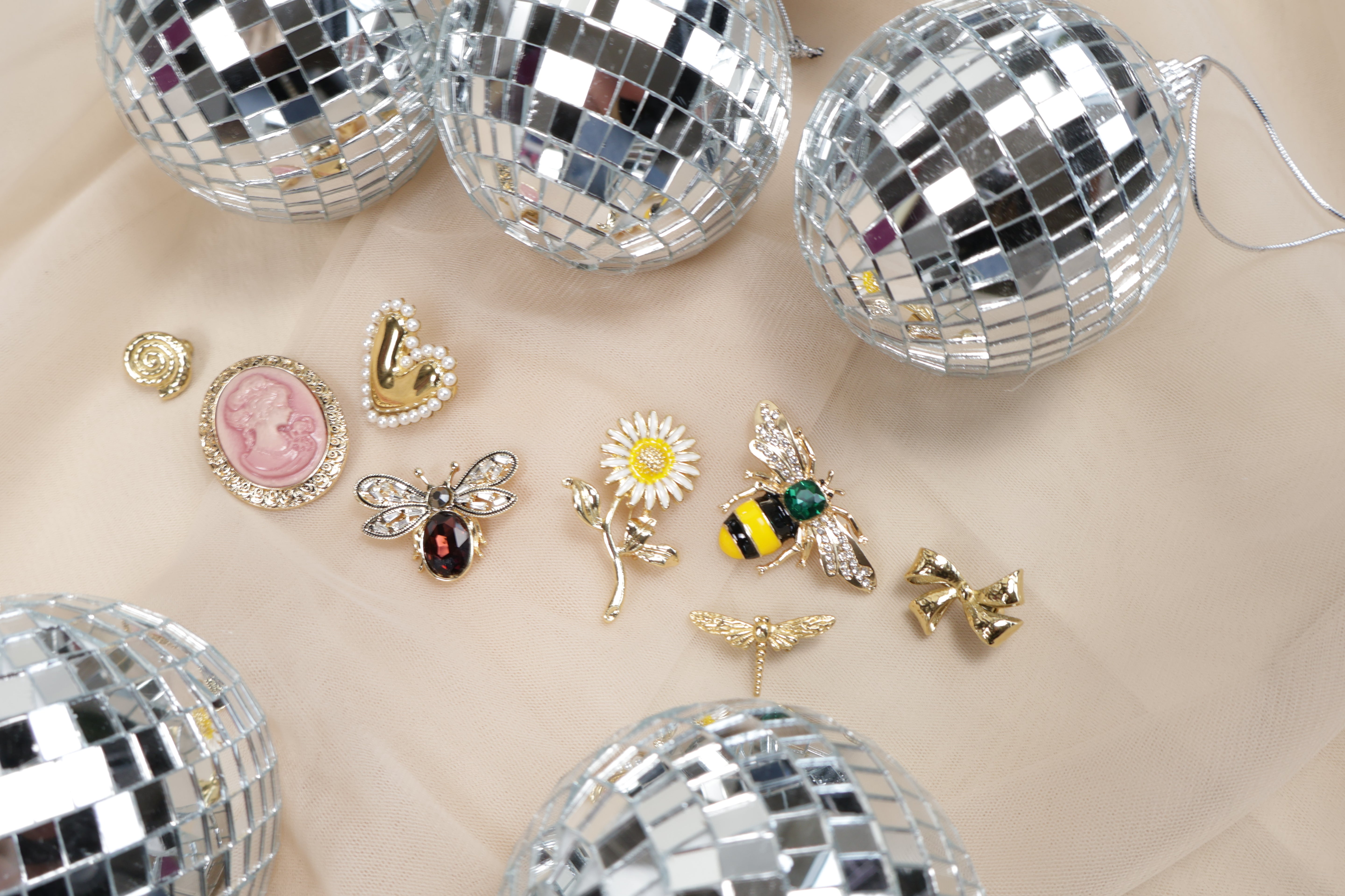 Various brooches on a beige background with disco balls

